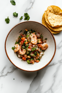 bowl of shrimp ceviche garnished with cilantro, served alongside crispy tortilla chips for a refreshing appetizer.