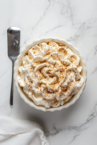 This image shows the creamy vegan whipped cream being served in a bowl with a spoon, ready to be added to desserts or enjoyed on its own.