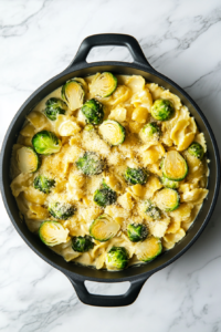 this image shows A beautifully plated dish of vegan creamy garlic Brussels sprouts pasta, garnished with shredded vegan Parmesan, ready to be enjoyed as a comforting and flavorful meal.