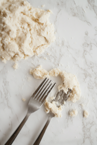 This image shows hands pulling apart the cooked dough into shredded pieces, creating a texture similar to chicken.