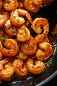 This image shows shrimp sizzling in the skillet, fully cooked, and coated in a rich honey garlic glaze, ready to be plated.