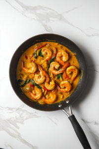 This image shows the creamy curry sauce gently simmering with shrimp and bell peppers, thickening into a rich and flavorful base.