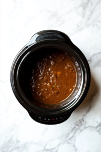 This image shows a top-down shot of the slow cooker, where the French Onion Soup is simmering, blending the flavors of the caramelized onions and broth.