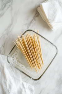 This image shows wooden skewers soaking in water to prevent them from burning during the grilling process.