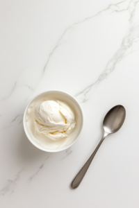 This image shows vanilla ice cream left at room temperature in a container until it becomes soft and easy to spread for layering in the peach cream pie.