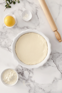 This image shows dough being pressed and spread evenly into a pie pan, creating the base for the vegan brownie pie before baking.