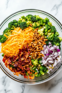 This image shows crispy crumbled bacon being scattered over the salad ingredients in the bowl, adding a smoky and savory element to the dish.