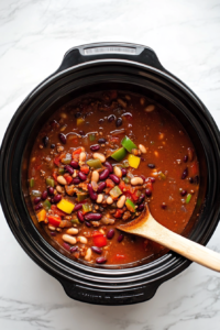 This image shows all the ingredients in the slow cooker being stirred together with a large spoon, ensuring the flavors are evenly distributed.