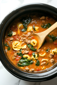 This image shows the soup being stirred in the crockpot, ensuring the tortellini and spinach are evenly distributed before the final cooking stage.