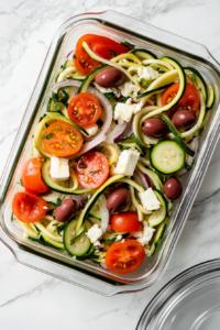 This image shows leftover Greek zucchini salad being placed into an airtight container to keep it fresh for later enjoyment.