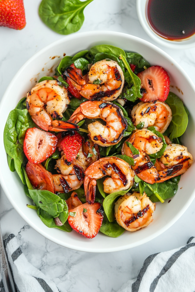 This image shows a refreshing summer shrimp salad in a white bowl, featuring shredded lettuce, diced red onions, and a light dressing tossed together for a perfect summer dish.