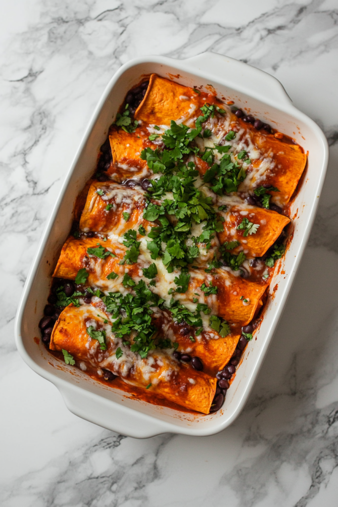 This image shows a rectangular white dish filled with sweet potato and bean enchiladas, smothered in tangy salsa verde and melted cheese, making a comforting and flavorful vegetarian meal.