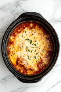 This image shows a generous final layer of shredded mozzarella cheese being added on top of the lasagna in the slow cooker for a perfectly melty finish.