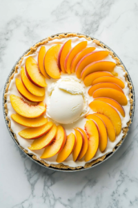 This image shows fresh peach slices being arranged neatly on top of the pie, adding a decorative and flavorful finishing touch to the dessert.