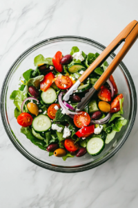 This image shows the salad being tossed to ensure the vegetables and dressing are evenly mixed, creating a well-coated and flavorful Keto Greek Cucumber Salad.