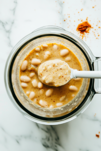 This image shows a portion of the Crockpot White Chicken Chili being transferred to a blender, offering an alternative method to achieve a creamy texture for the dish.