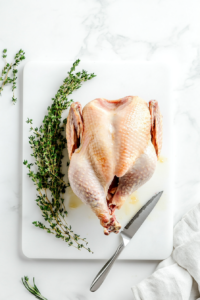 This image shows a turkey breast being trimmed with scissors, removing excess skin for a cleaner and leaner preparation.