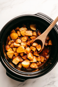 This image shows chopped apples and spices being placed into a slow cooker, ready to be transformed into a warm and comforting applesauce.