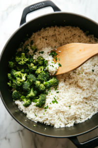 This image shows rice being cooked in a pot with savory broth, adding rich flavor to the casserole base.