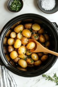 This image shows freshly chopped rosemary and parsley being sprinkled over the cooked potatoes, along with a touch of flaked sea salt for a burst of flavor.