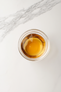 This image shows a bowl of freshly mixed dressing resting on a countertop, allowing the ingredients to meld together for a deeper, more balanced flavor before being added to the salad.