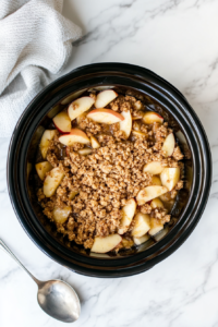 This image shows the apple mixture being carefully added to the crockpot, preparing for slow cooking to turn it into a warm, delightful dessert.