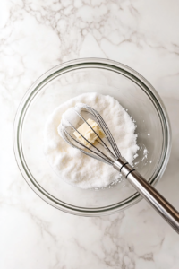 This image shows butter and sugar being whipped together in a mixing bowl until pale and fluffy, an essential step for a light and tender pound cake.