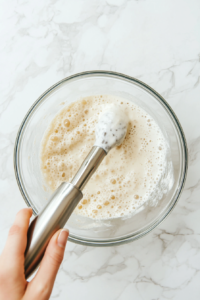 This image shows a hand blender emulsifying the glaze mixture, making it silky and lump-free for a flawless finish.