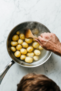 This image shows diced potatoes boiling in a pot of hot water until tender, preparing them for mashing.