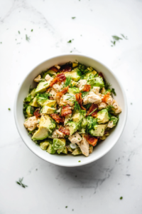 This image shows the lemon dressing being drizzled over the salad, followed by gentle tossing to coat all ingredients evenly.