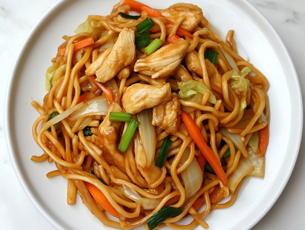 This image shows a plate of Chicken Spaghetti Lo Mein with tender chicken pieces and noodles tossed in a flavorful sauce made with soy sauce, oyster sauce, dark soy sauce, Shaoxing wine, and sesame oil.