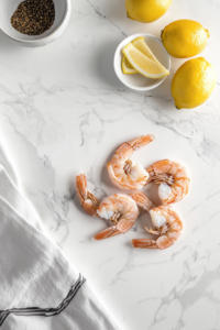 This image shows perfectly chilled shrimp arranged on a serving plate, garnished with fresh lemon wedges for a bright, citrusy finish, making them irresistibly fresh and flavorful.