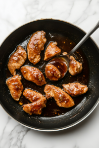 This image shows chicken pieces being turned in the simmering maple sauce, ensuring every bite is coated in the rich, sticky glaze.