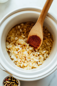 This image shows diced onions being sautéed in the slow cooker, softening and developing a rich, savory flavor for the taco soup.