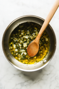 This image shows finely chopped onions and garlic sizzling in a pan, turning golden brown and releasing their aromatic flavors.