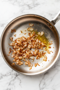 This image shows minced garlic being added to the pan, infusing the sauce with a rich, savory flavor.