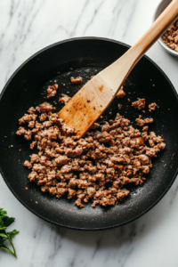 This image shows ground sausage being cooked in a skillet until browned and fully cooked, adding savory flavor to the breakfast casserole.