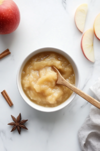 This image shows freshly made applesauce cooling in a white bowl, ready to be served as a warm or chilled treat.