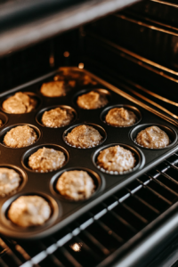 This image shows a mini muffin tin inside the oven, where cornbread poppers are baking to a golden brown finish.