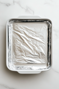 This image shows the baking dish being covered with foil, helping the lasagna cook evenly and retain moisture during baking.