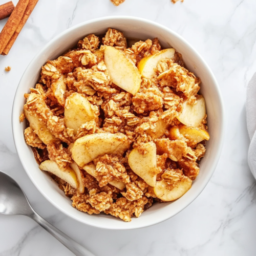 This image shows Crockpot Apple Crisp served in a white bowl, featuring chunks of tender apple, golden crumbs, and crunchy walnuts, making for a warm, comforting dessert.