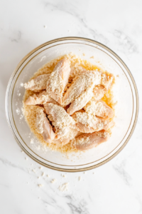 This image shows a chicken medallion being coated in a seasoned flour mixture, ensuring a light, crispy texture when cooked.