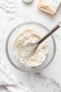 This image shows a bowl of seasoned flour mixture, prepared for coating the chicken medallions before cooking.