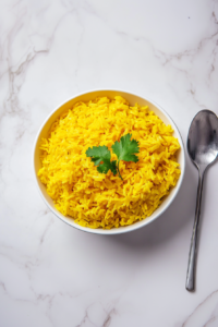 This image shows a fork gently fluffing the cooked turmeric rice, separating the grains for a light and fluffy texture before serving.