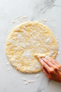 This image shows hands gently folding the bread dough, building structure and strength before baking.