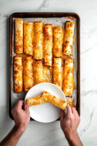 This image shows a plate of crispy baked potato taquitos, slightly cooled and ready to be served with dipping sauces.