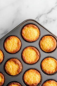 This image shows cornbread poppers resting on a wire rack, cooling slightly before being glazed with honey butter.