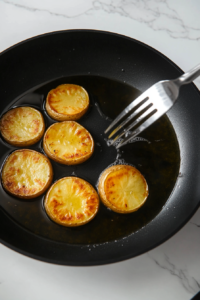 This image shows the potato stacks sizzling in oil, turning golden brown and crispy on the first side.