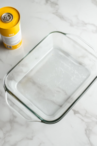 This image shows a baking dish being lightly greased, ensuring the chicken fajita casserole bakes evenly without sticking.