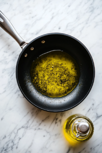 This image shows a skillet with olive oil heating up, ready to sear the seasoned chicken to a golden brown perfection.